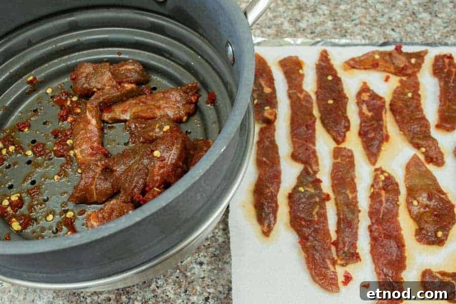 Cherry Bomb Beef Jerky: Spicy-Sweet Gourmet Snack 11 Patting dry jerky strips on paper towels