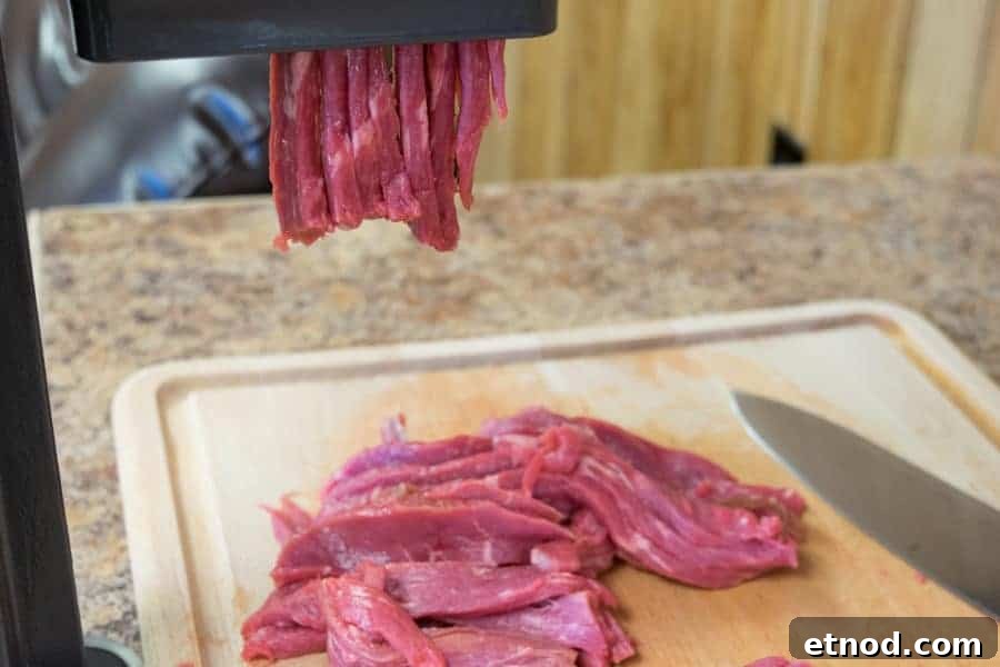 Cherry Bomb Beef Jerky: Spicy-Sweet Gourmet Snack 5 Beef Jerky slicer slicing beef for jerky onto a cutting board with knife