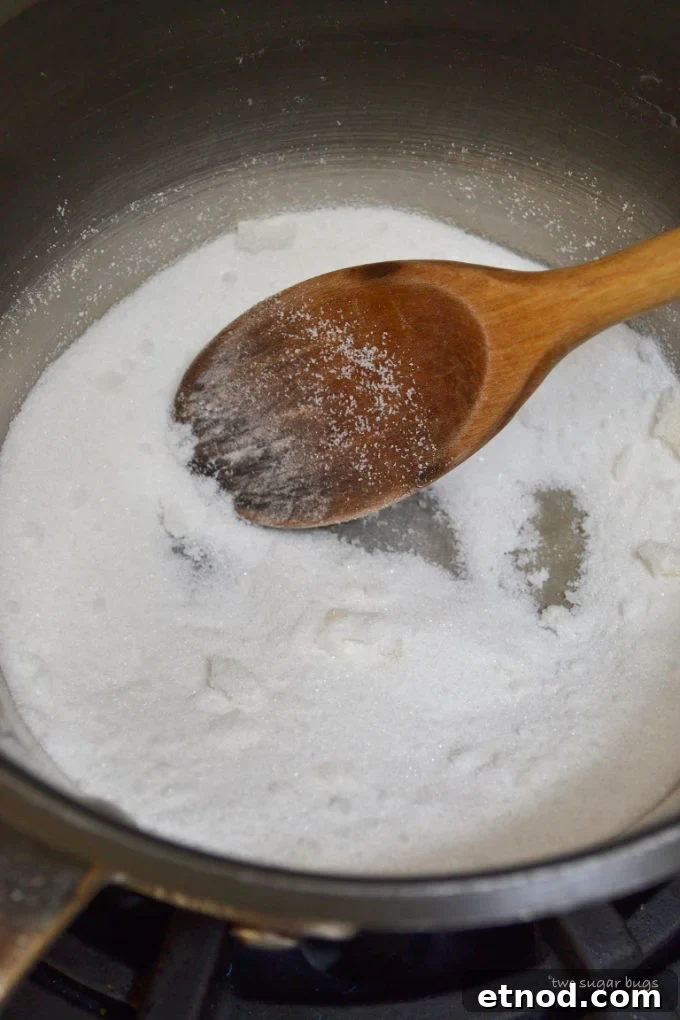 Creamy Cookie Butter Caramel Sauce Recipe 5 sugar in a sauce pan with a wooden spoon in the initial melting stage