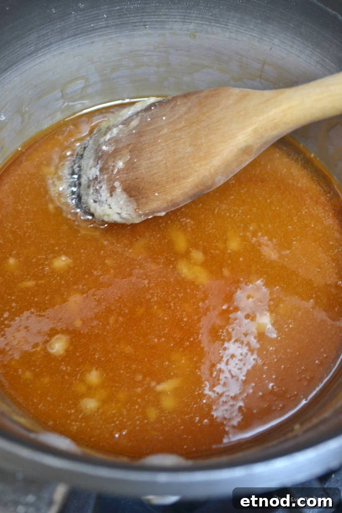 Creamy Cookie Butter Caramel Sauce Recipe 8 sugar melting in a sauce pan with a wooden spoon