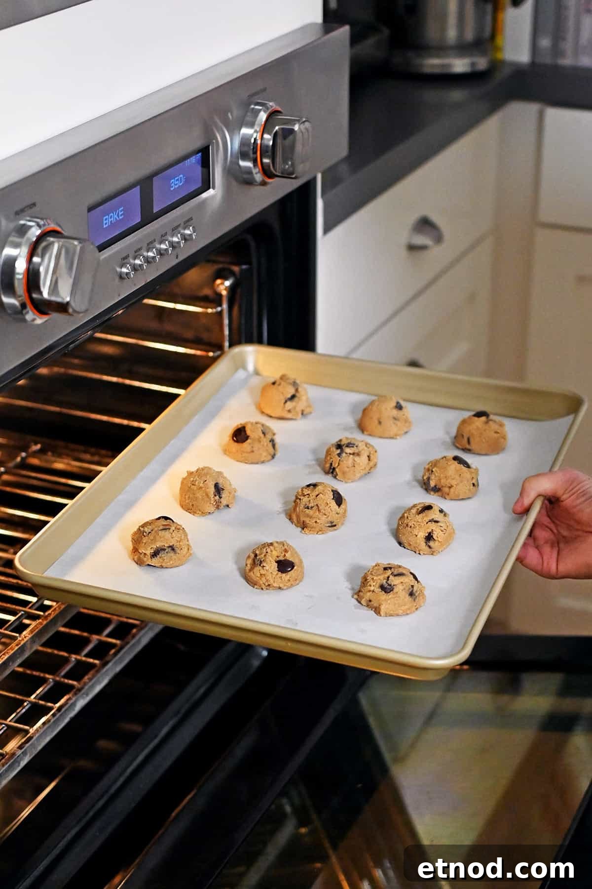 Soft Banana Chocolate Chip Cookies — Paleo Grain-Free Recipe 13 Placing a rimmed baking pan filled with banana cookie dough balls into an open oven to bake.