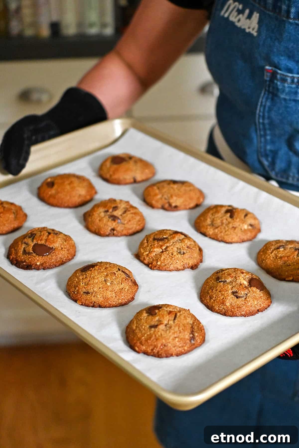 Soft Banana Chocolate Chip Cookies — Paleo Grain-Free Recipe 14 A person is holding a tray of freshly baked paleo banana chocolate chip cookies right out of the oven.