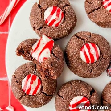 Chocolate Peppermint Kiss Cookies Recipe for Holiday Baking 11 chocolate peppermint kiss cookies on white plate on red tile background.