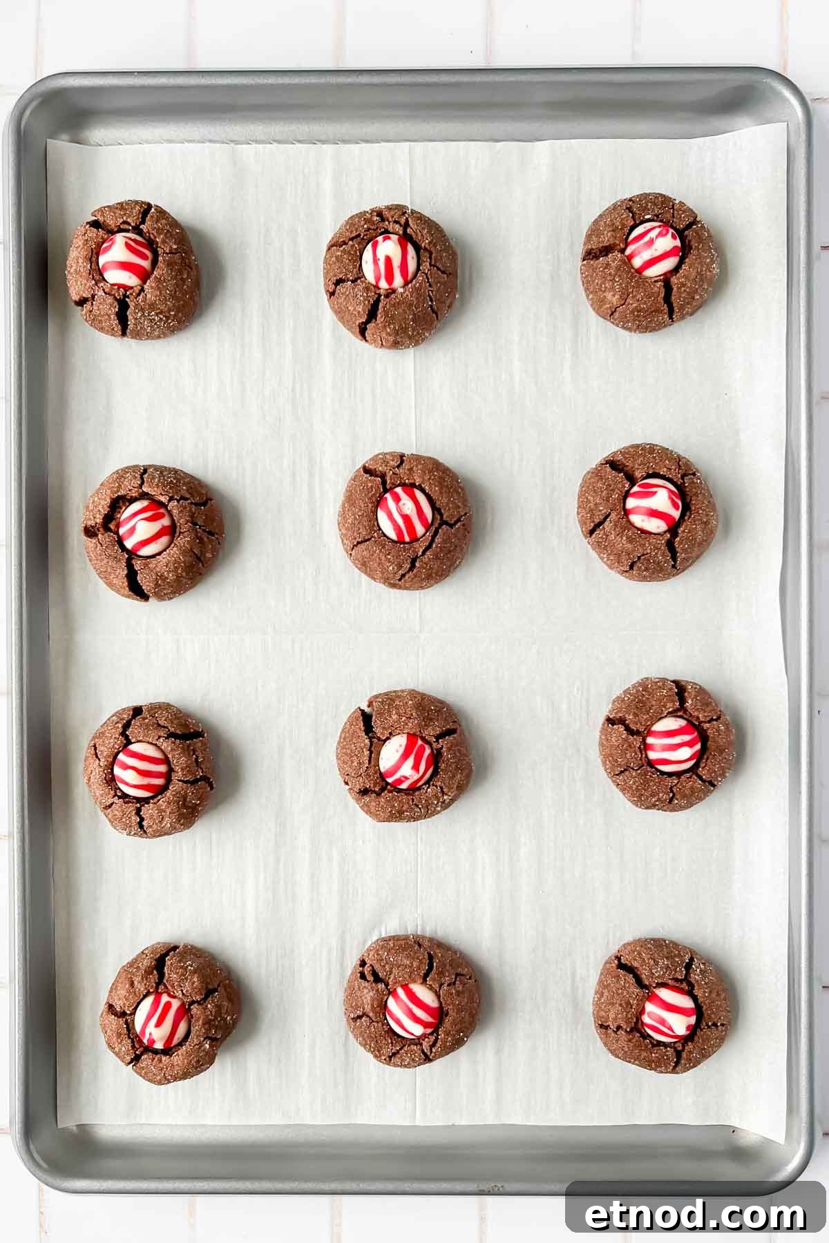 Chocolate Peppermint Kiss Cookies Recipe for Holiday Baking 9 12 chocolate peppermint kiss cookies aligned on silver baking tray lined with parchment.