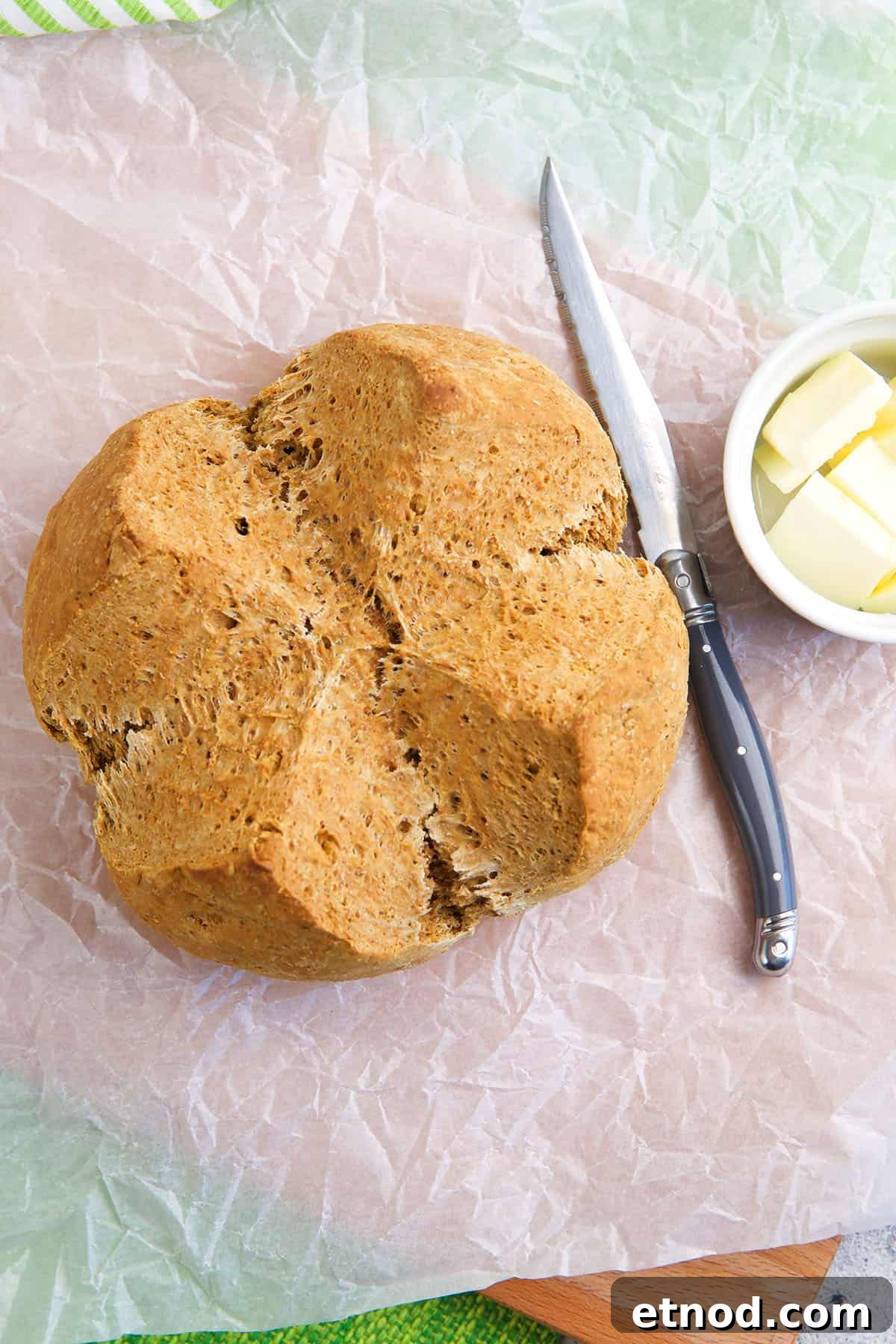 Traditional Irish Brown Bread Recipe — Rustic Soda Bread Guide 3 A whole loaf of bread is placed next to a knife and butter.