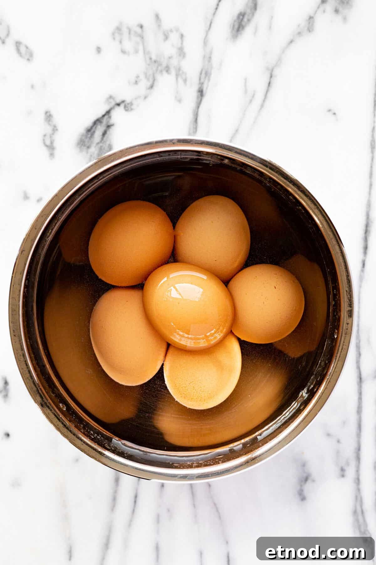 Bowl of water with hard boiled eggs in it.