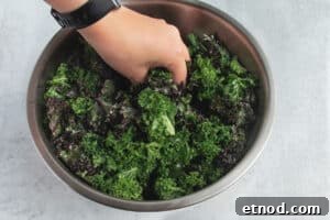 Kale Salad with Roasted Beets and Orange Vinaigrette 11 Picture of kale in a large bowl being massaged.