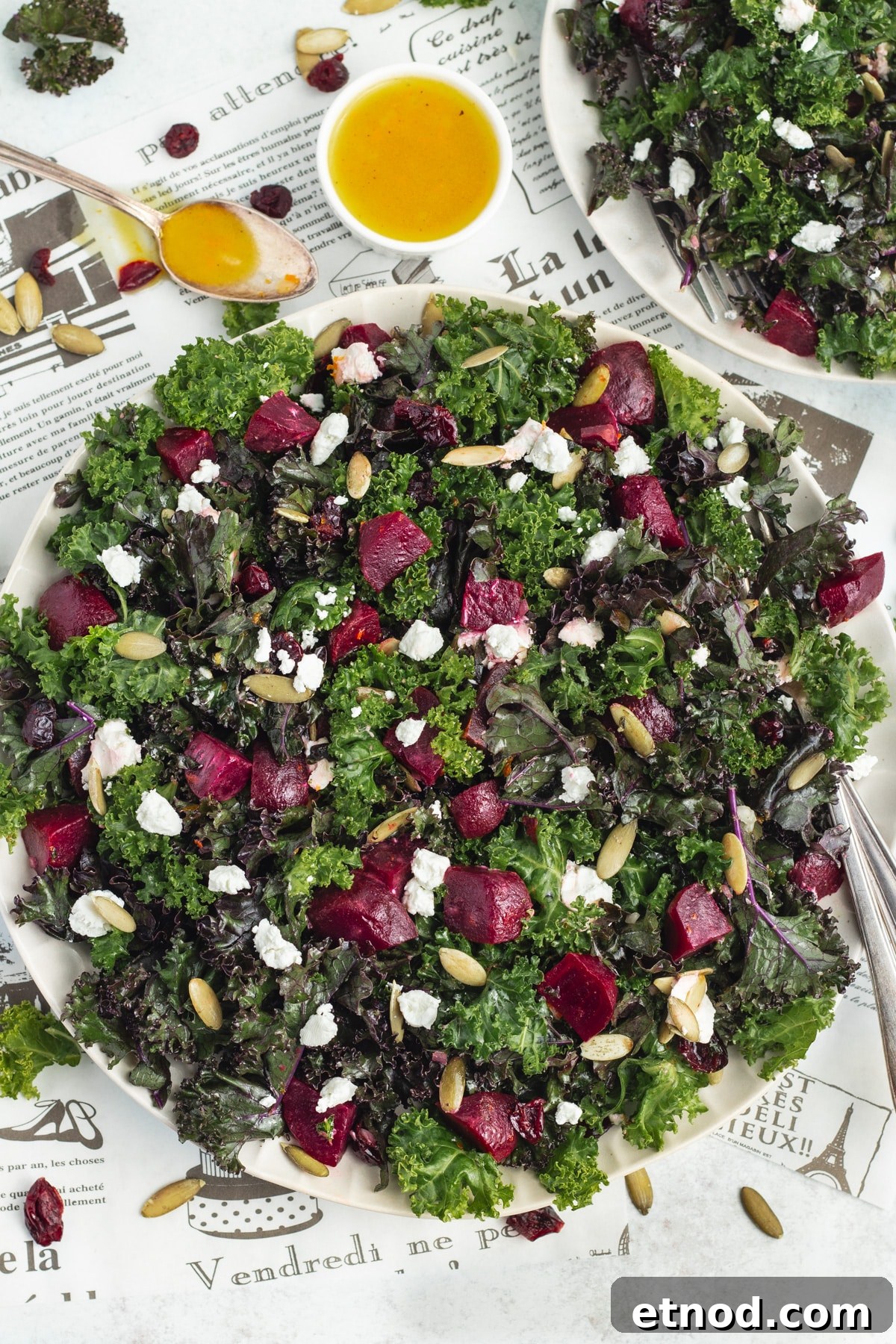 Kale Salad with Roasted Beets and Orange Vinaigrette 4 This is a picture of a plate with the kale and beet salad with goat cheese and pumpkin seeds and a little bowl with the orange vinaigrette.