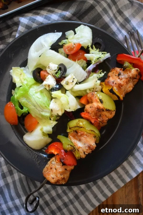Cajun Chicken Kebabs on a black plate with a salad