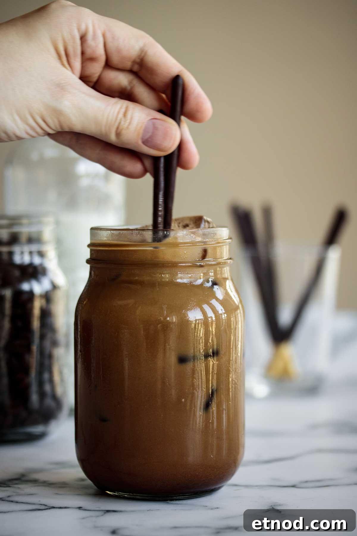 Iced Chocolate Almond Milk Shaken Espresso Recipe 5 Hand stirring beverage, mixing almond milk with coffee and chocolate mixture.