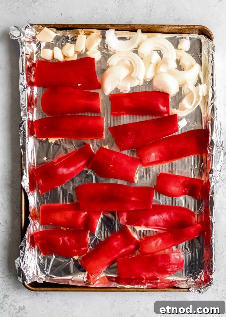 Creamy Roasted Red Pepper Soup with Garlic and Basil 4 sliced red peppers, cut onion, and garlic cloves on a prepared baking sheet