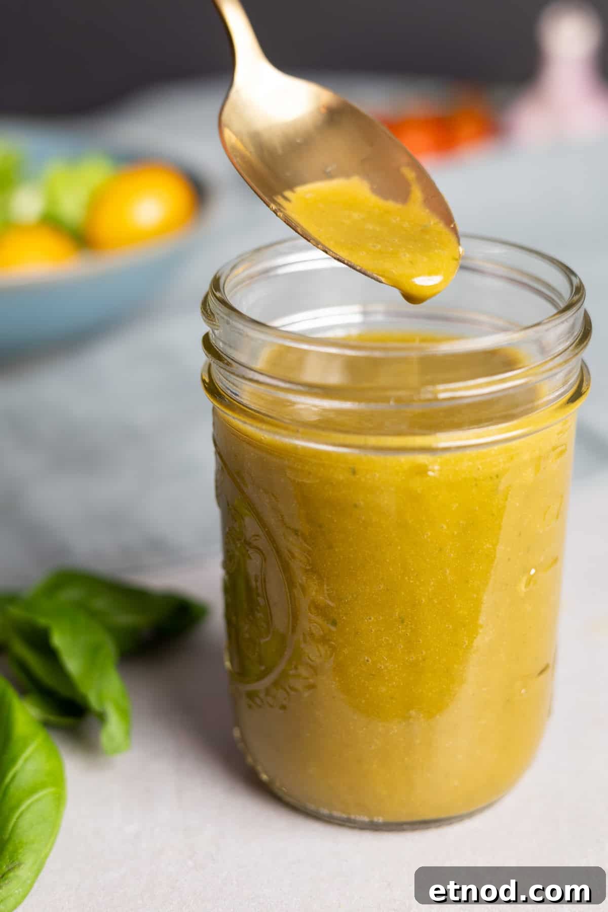 Basil balsamic vinaigrette in a small mason jar with a spoon taking out a bit.