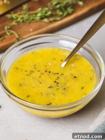 A close-up of lemon thyme vinaigrette in a glass bowl with a spoon inside.