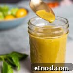 Basil balsamic vinaigrette in a small mason jar with a spoon taking out a bit.