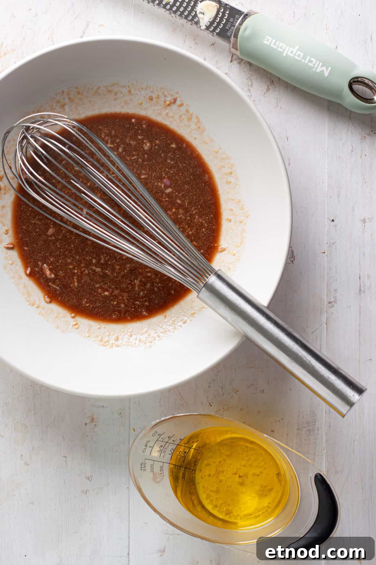 Basil balsamic vinaigrette getting whisked together in a medium bowl.