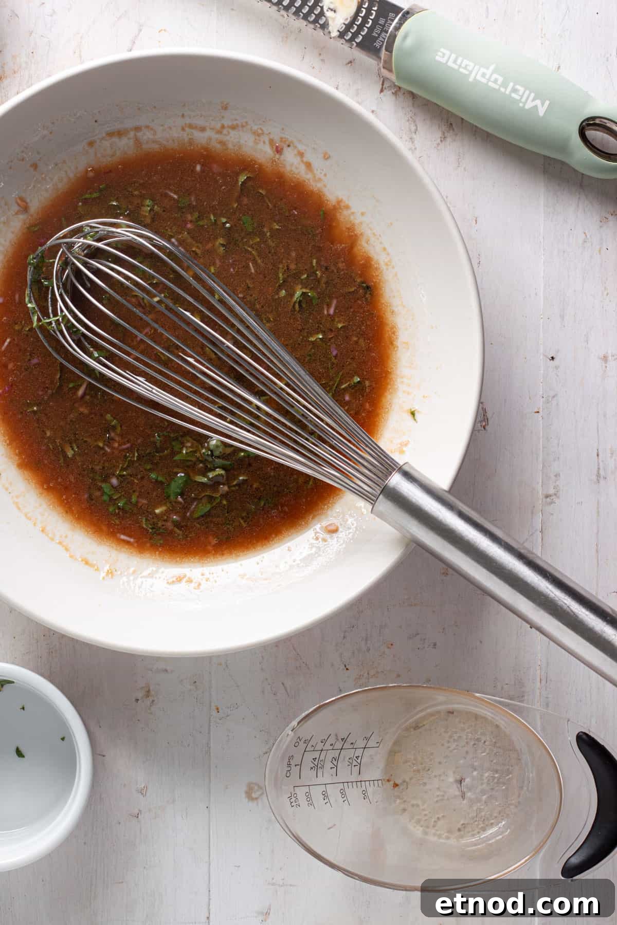 Oil whisked into a basic balsamic vinaigrette in a medium bowl.