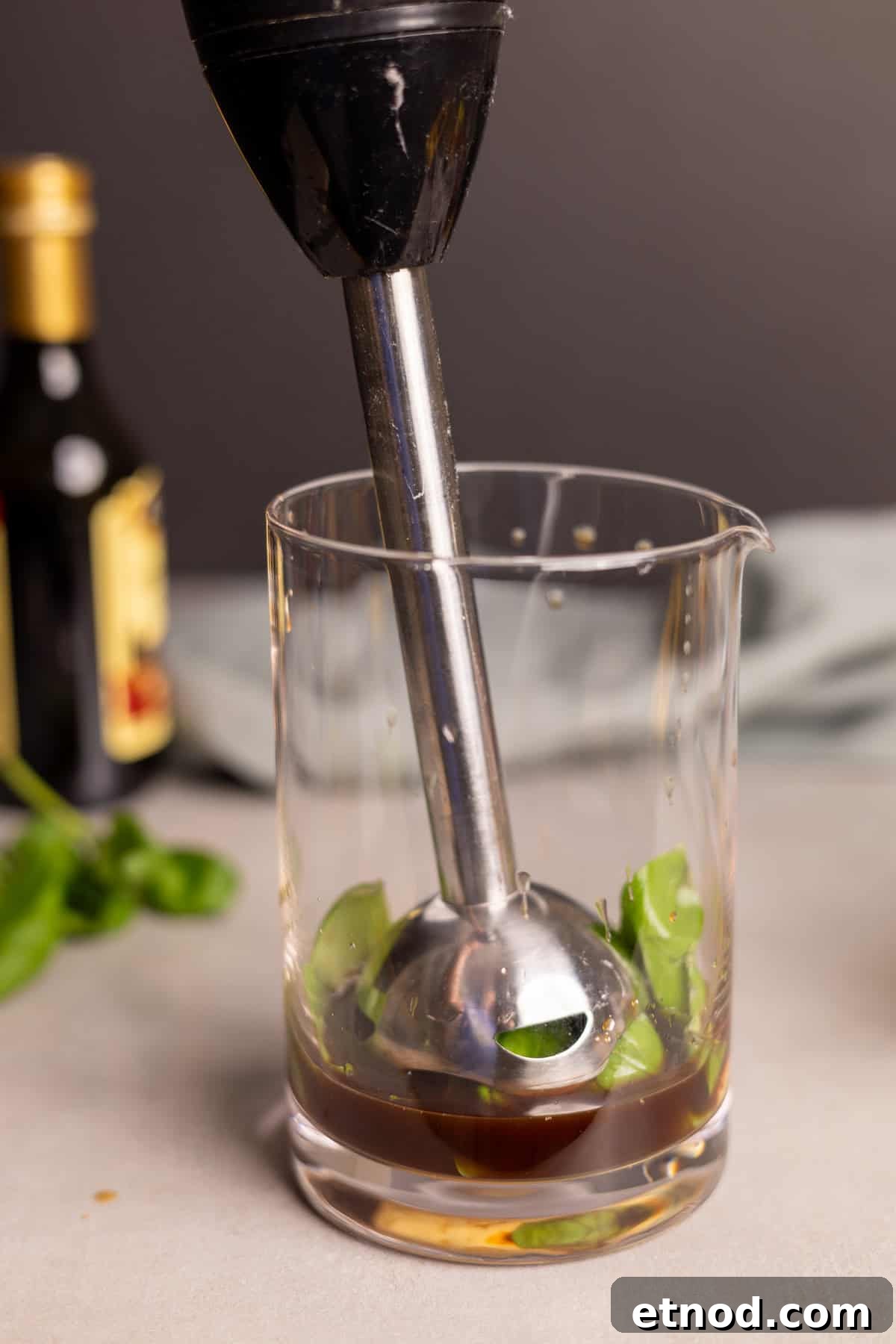 Ingredients for basil balsamic vinaigrette in a glass jar with an immersion blender.