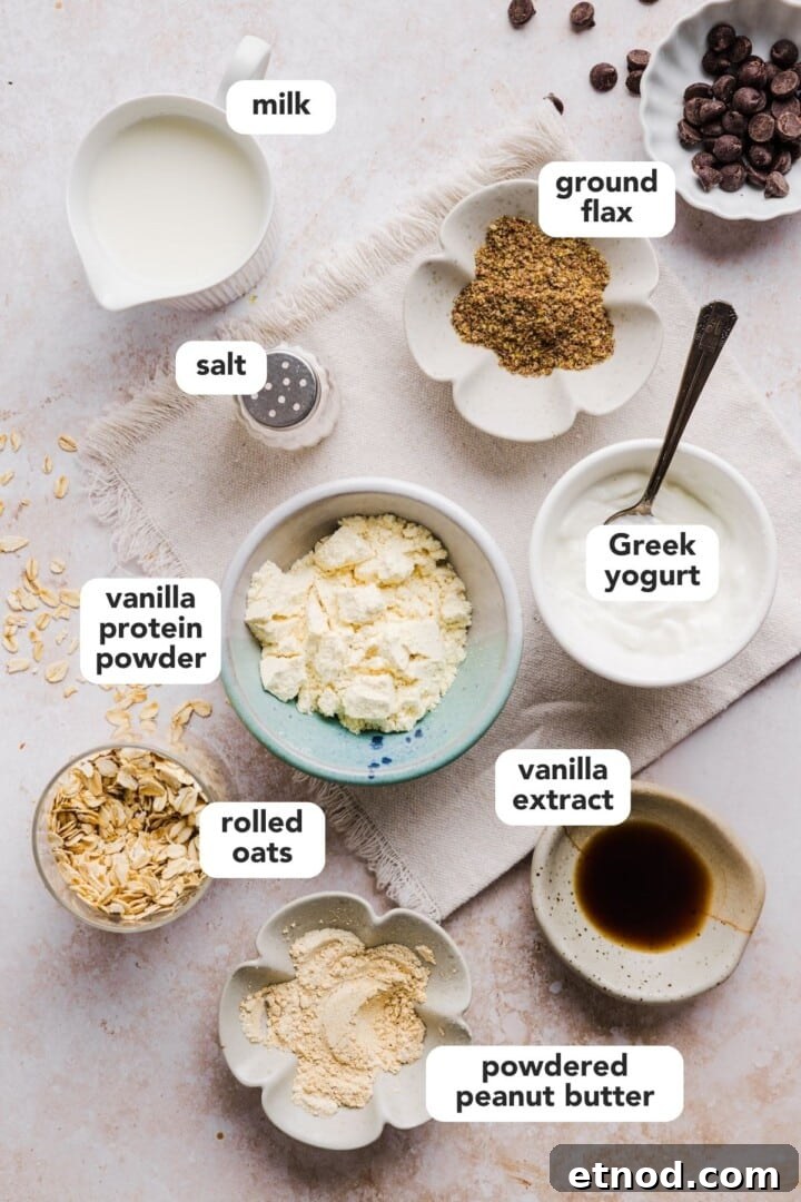 Ingredients for cookie dough overnight oats displayed in small bowls on a marble counter.