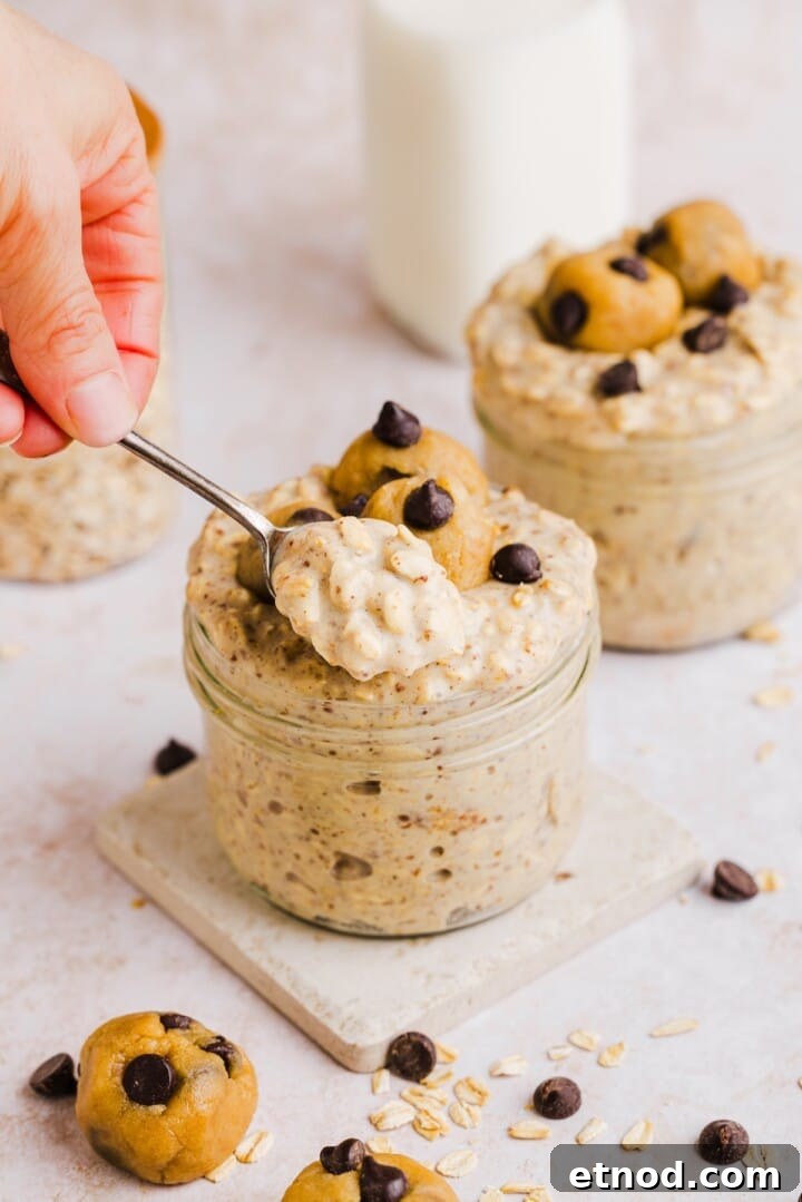 Woman's hands holding a spoon up with cooke dough overnight oats.