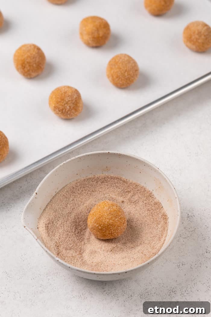 Chewy Pumpkin Snickerdoodles Recipe for Fall Baking 7 Dough ball being rolled in a spiced sugar mixture in a small bowl.