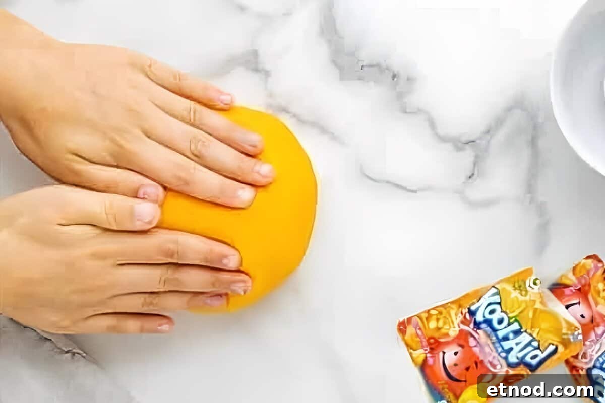 Make Homemade Kool-Aid Play Dough: Bright, Scented Recipe 14 Hands kneading orange play-dough.