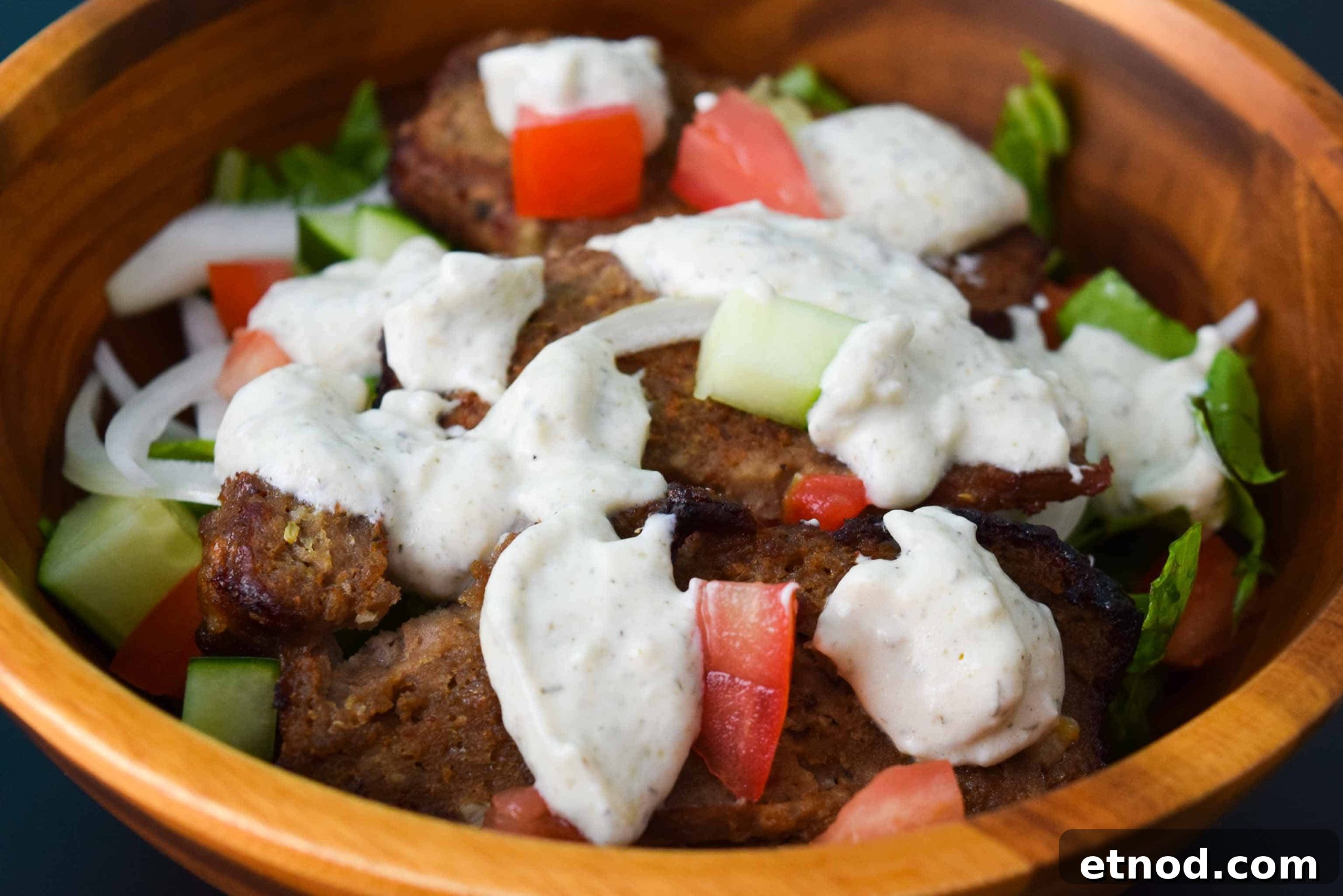 How to Make Authentic Gyro Meat at Home 4 Gyro Meat in salad bowl close up topped with tzatziki