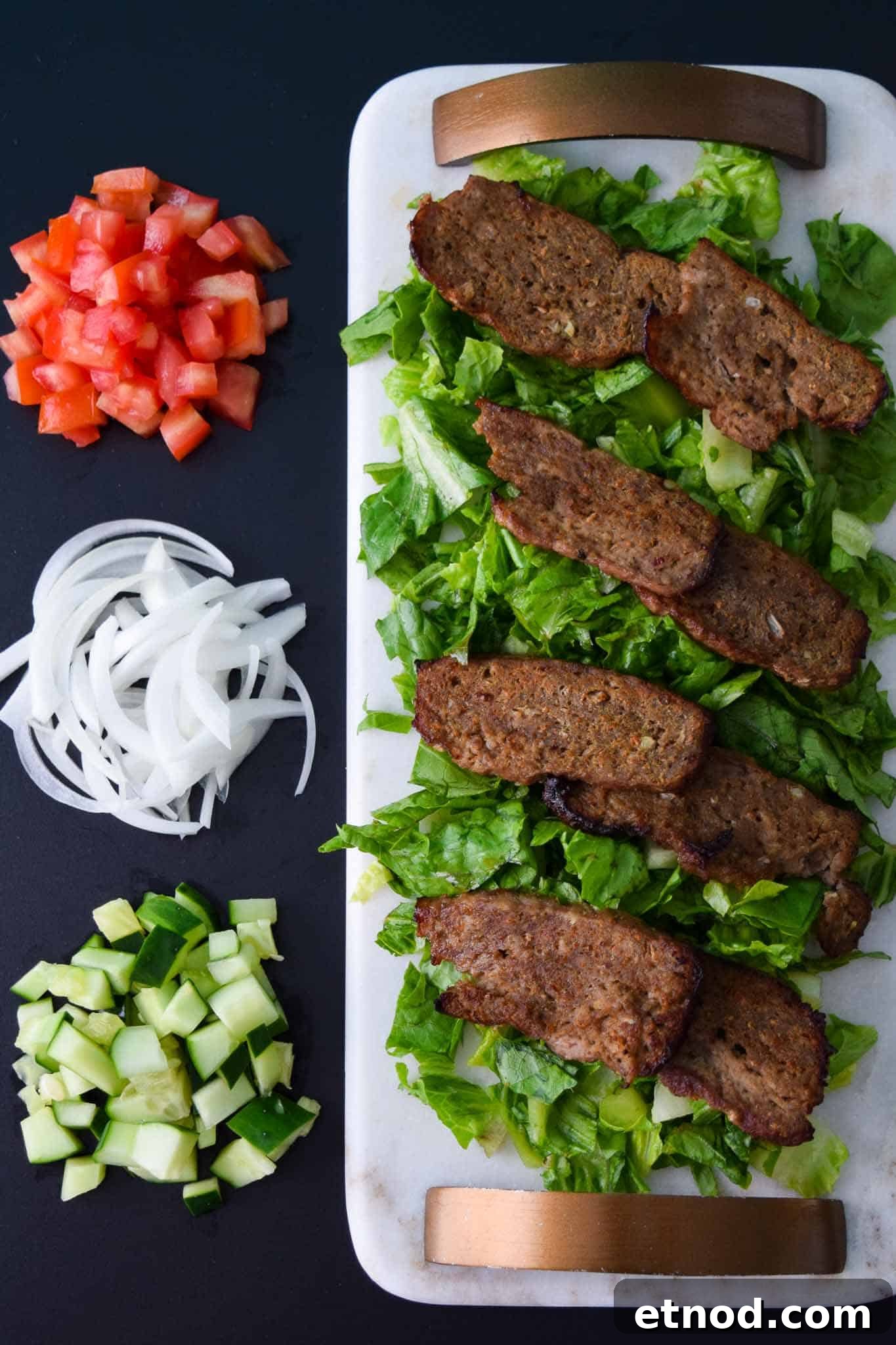How to Make Authentic Gyro Meat at Home 3 Gyro Meat on white platter with toppings beside it overhead shot