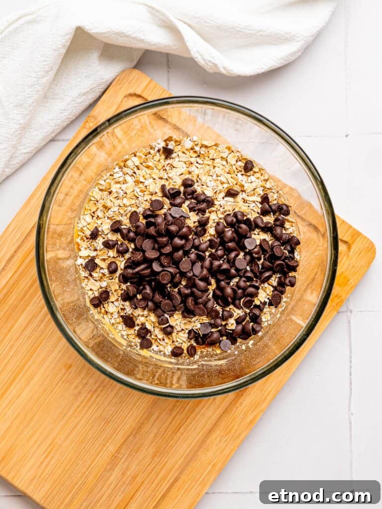 Bowl with peanut butter and liquid sweetener combined and oats and mixins added in.