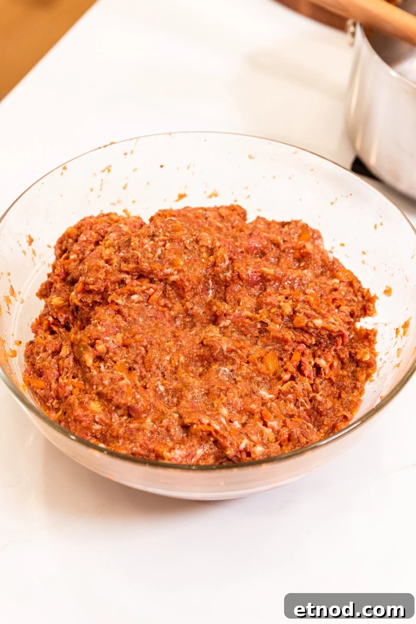 Classic Comfort Meatloaf Recipe for Perfect Weeknight Dinners 14 Glass metal bowl with mixed meat mixture for meatloaf sitting on white surface.