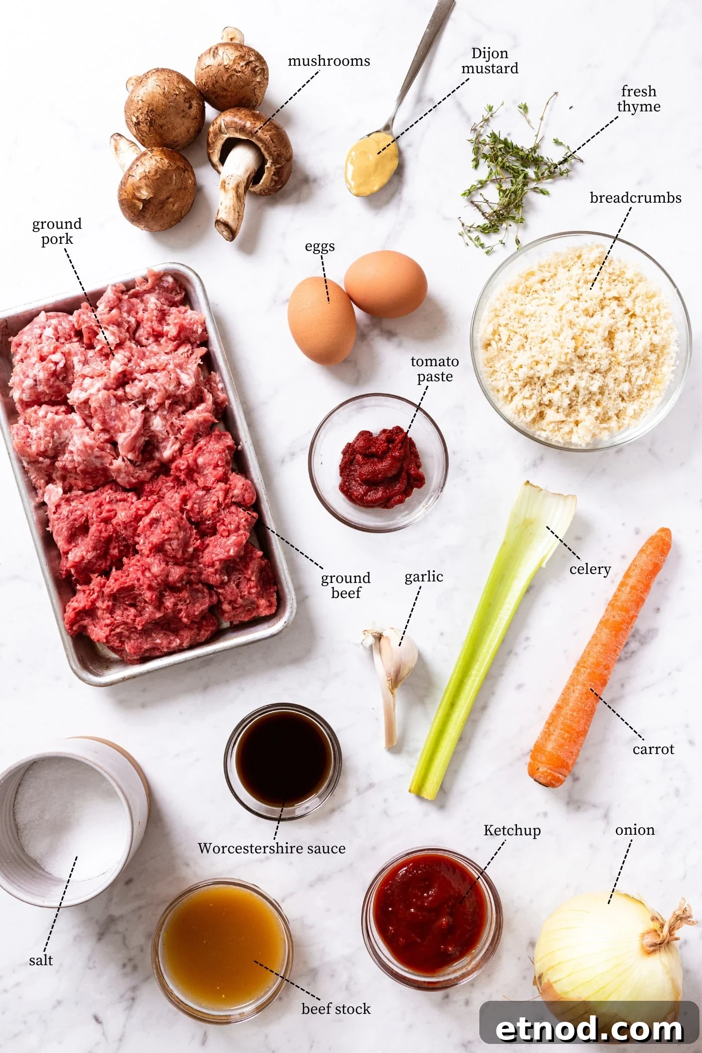 Classic Comfort Meatloaf Recipe for Perfect Weeknight Dinners 4 Marble surface filled with all ingredients needed to prepare meatloaf including ground beef, ground pork, breadcrumbs, celery, carrot, eggs, spices, and more.