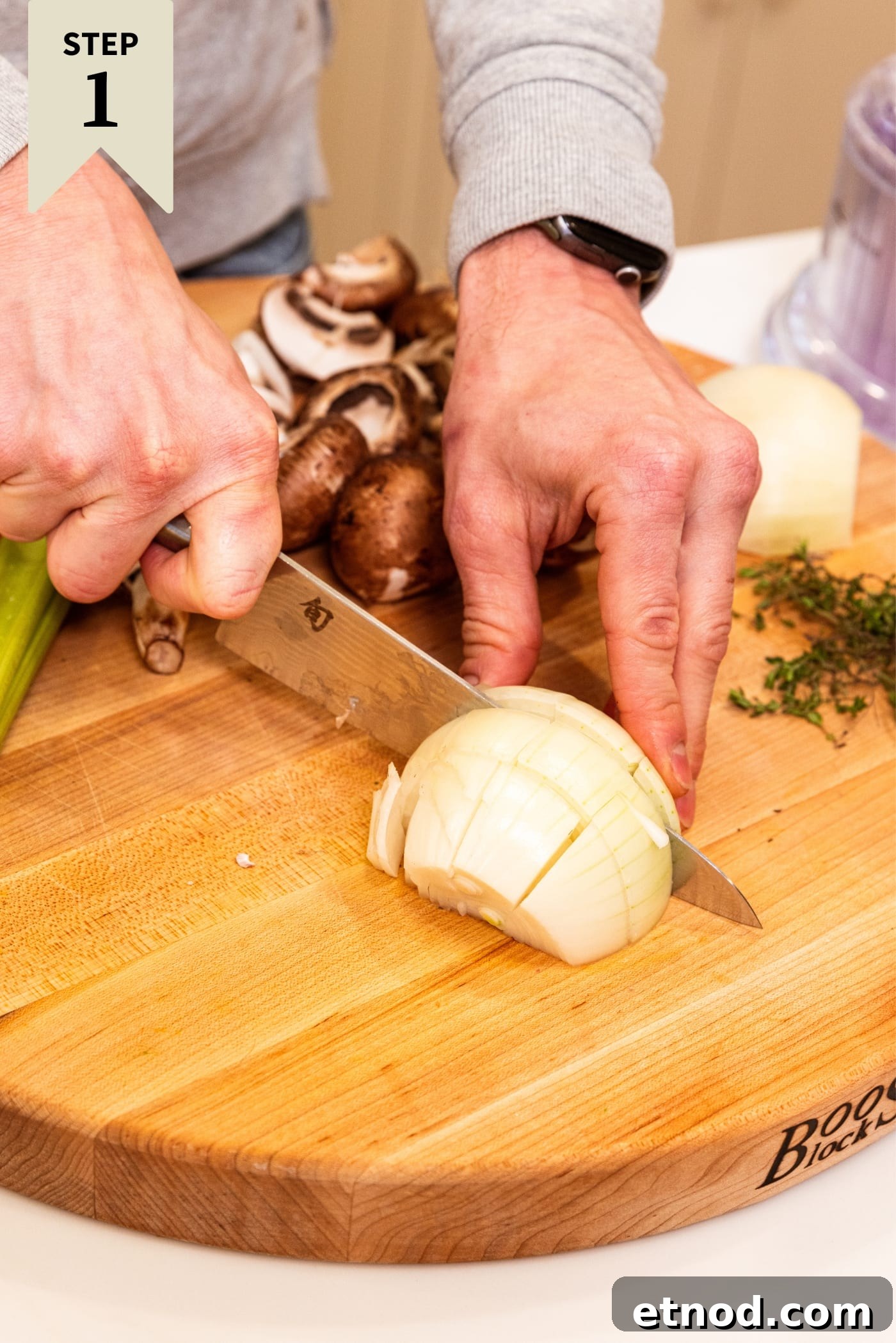 Classic Comfort Meatloaf Recipe for Perfect Weeknight Dinners 5 Hand using knife to slice an onion into large chunks on a wooden cutting board with other vegetables in background before being cut.