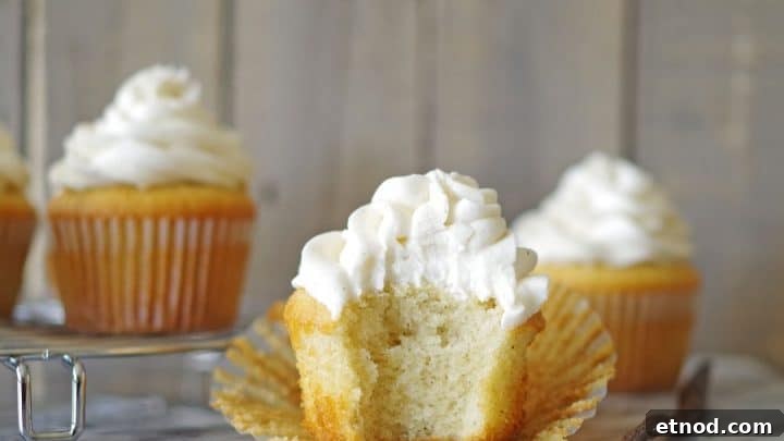 a gluten free vanilla bean cupcake with a bite out of it on a marble counter