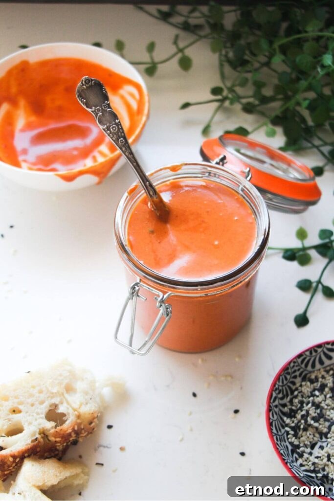 Roasted Garlic Butter Recipe: Creamy Spread for Bread & Cooking 11 Gochujang mayo in a small glass bowl with a gold spoon, on a grey marble background.