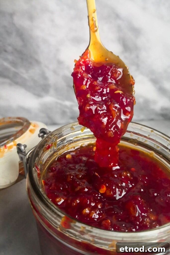 Roasted Garlic Butter Recipe: Creamy Spread for Bread & Cooking 12 Chilli jam falling off small gold spoon into glass jar.