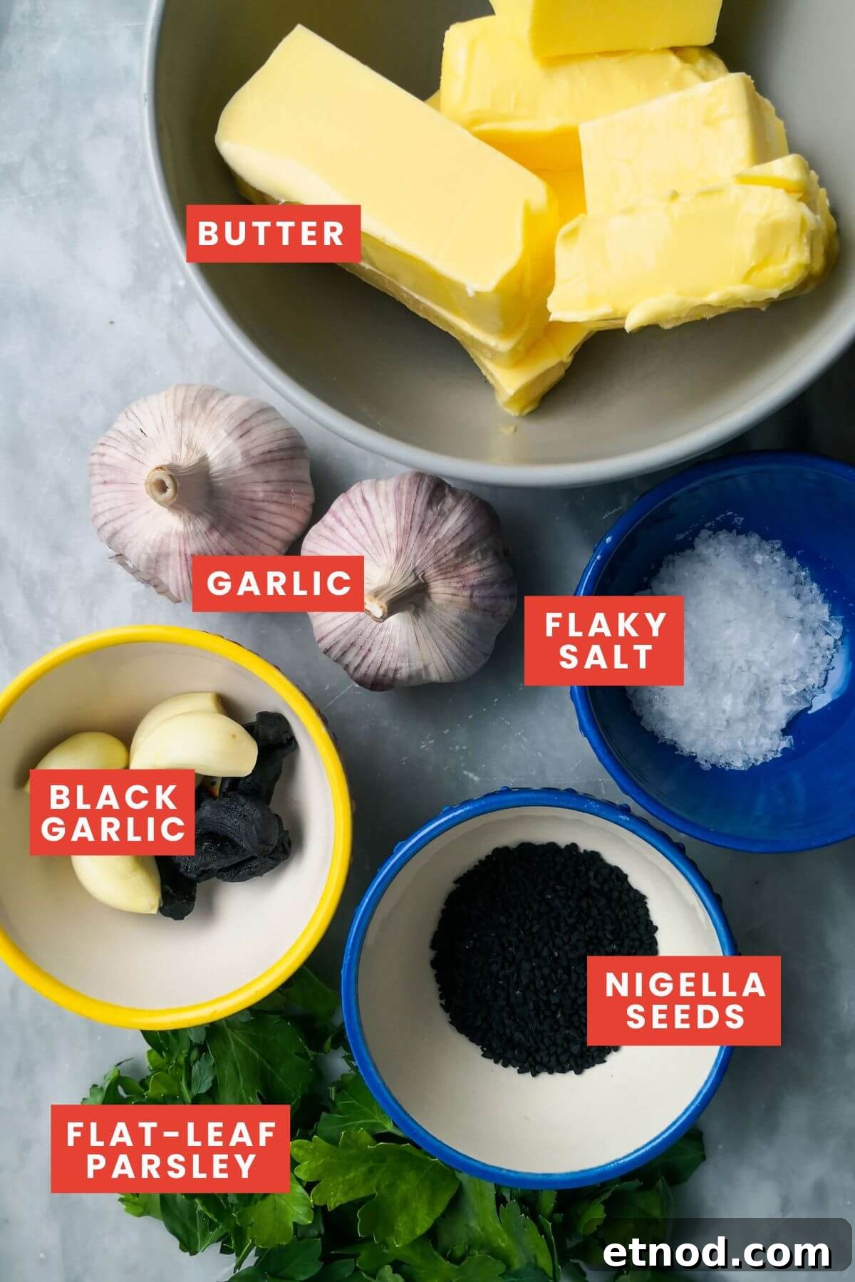 Roasted Garlic Butter Recipe: Creamy Spread for Bread & Cooking 3 Roasted garlic butter ingredients in small bowls on a grey marble background.