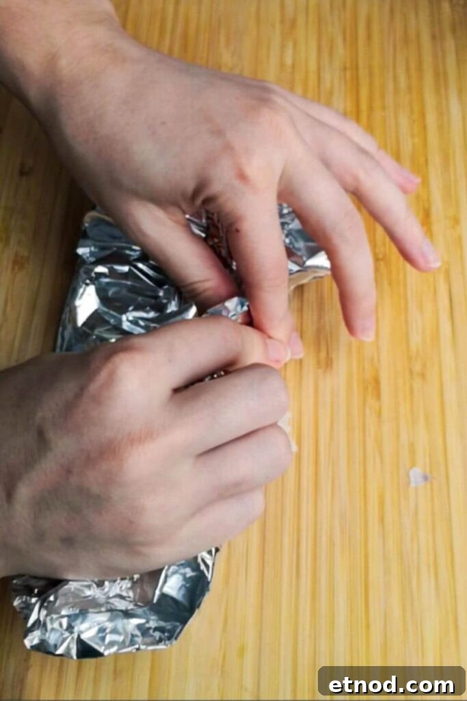 Roasted Garlic Butter Recipe: Creamy Spread for Bread & Cooking 5 Two hands wrapping up a baking foil package.