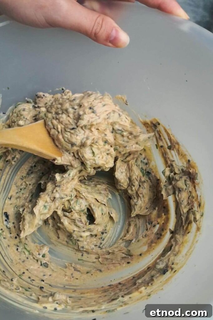 Roasted Garlic Butter Recipe: Creamy Spread for Bread & Cooking 9 Roasted garlic butter mixed together in a large mixing bowl with a wooden spoon.
