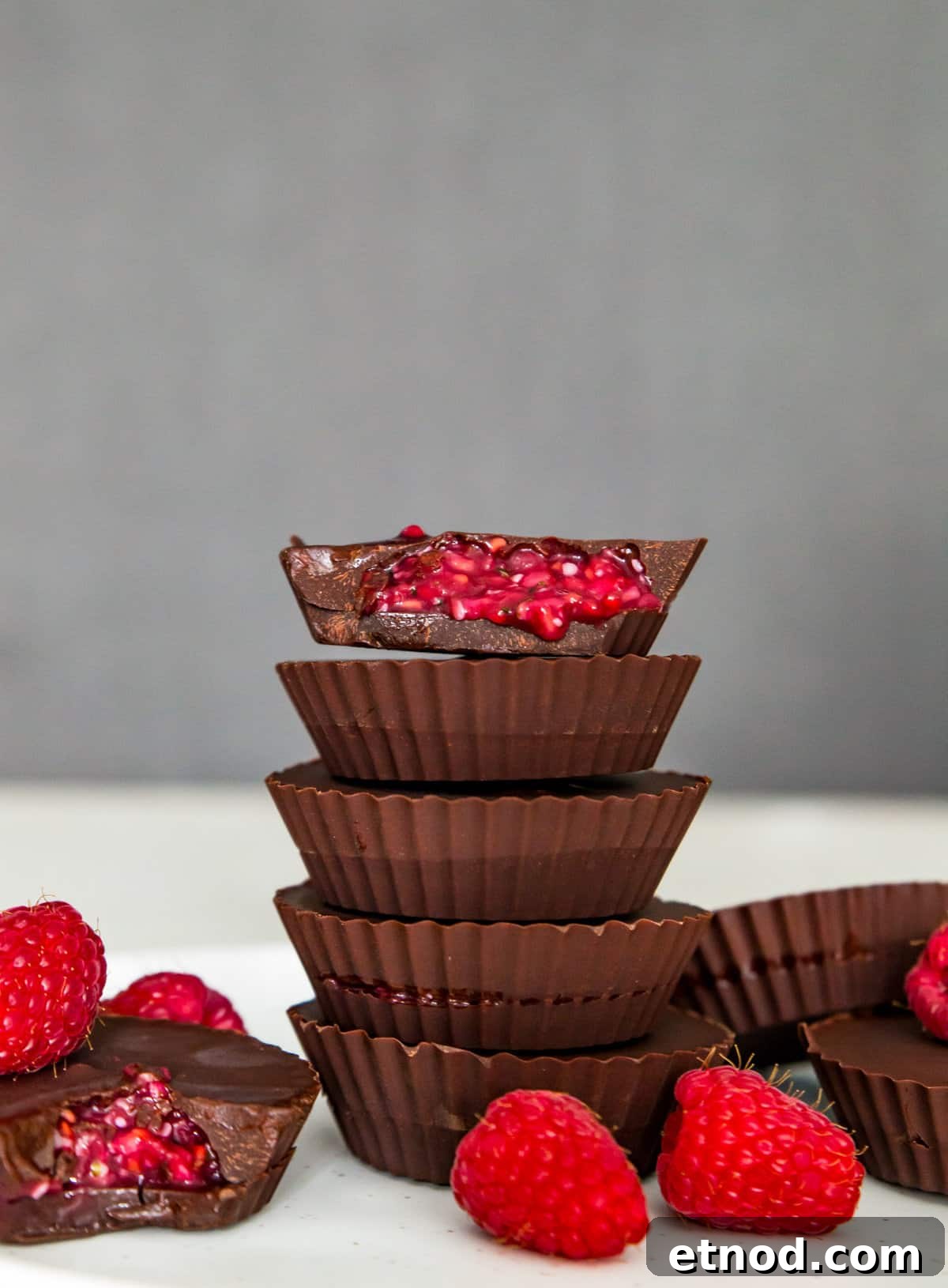 High-Protein Raspberry-Filled Chocolate Truffles 2 A stack of five chocolates and the top one has a bite out of it with a raspberry filling spilling out.