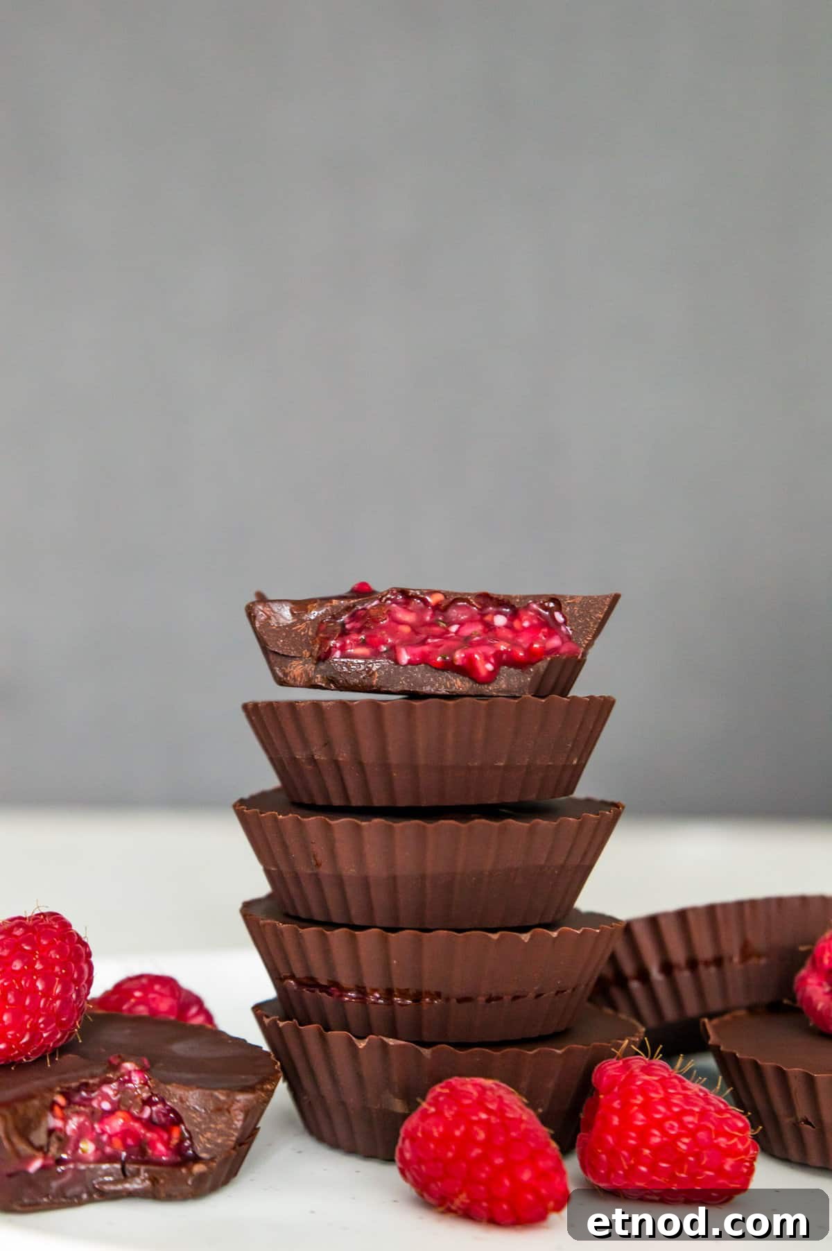 High-Protein Raspberry-Filled Chocolate Truffles 12 A stack of five raspberry filled chocolates and the top one has a bite out of it with the raspberry filling spilling out.
