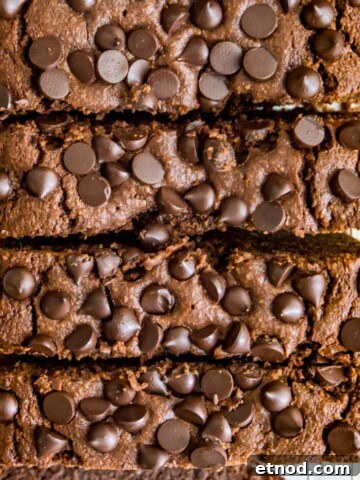 A loaf of double chocolate zucchini bread topped with chocolate chips cut into slices.