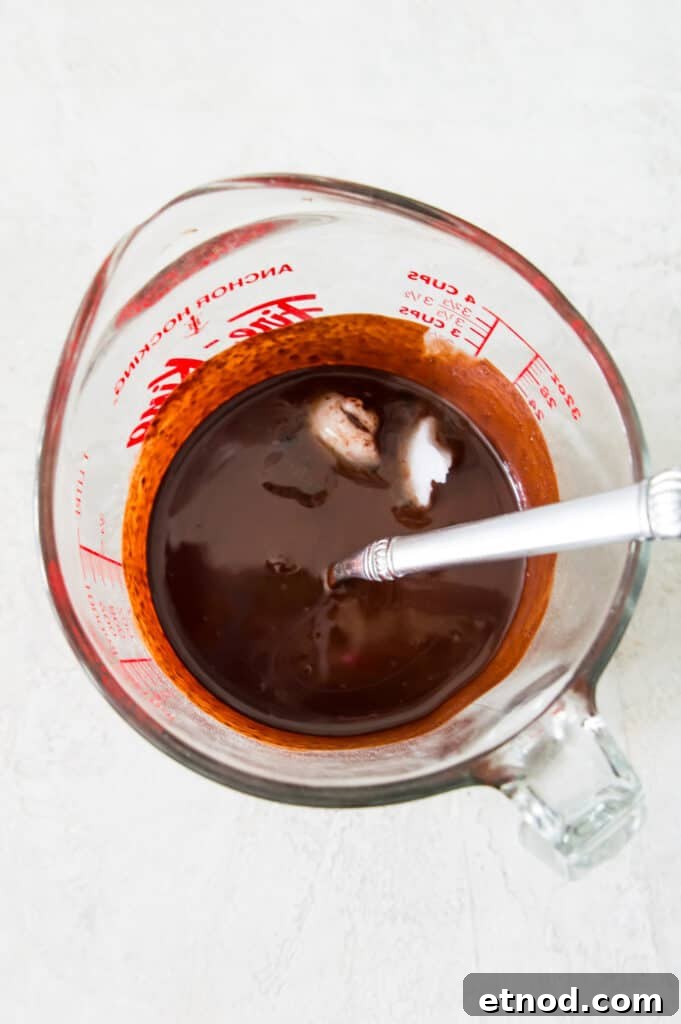 High-Protein Raspberry-Filled Chocolate Truffles 5 A glass measuring cup with melted chocolate and coconut oil in it.