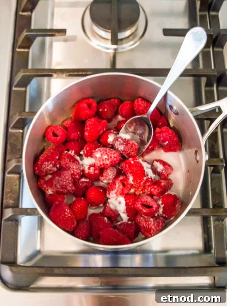 High-Protein Raspberry-Filled Chocolate Truffles 7 A saucepan on the stovetop with raspberries and coconut milk in it.