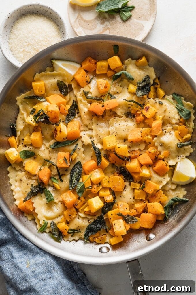 Brown Butter Ravioli with Roasted Butternut Squash Filling 2 Overhead view of a skillet with ravioli in a brown butter sage sauce with roasted butternut squash cubes, black pepper, and Parmesan cheese.
