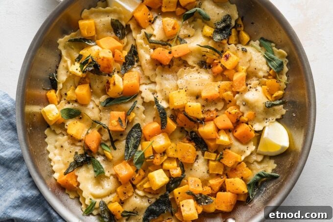 Brown Butter Ravioli with Roasted Butternut Squash Filling 9 Landscape oriented photo of a skillet with ravioli in a brown butter sage sauce with roasted butternut squash cubes, black pepper, and Parmesan cheese.