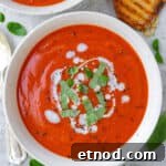 Dairy free tomato soup in a bowl with shredded basil leaves and coconut cream drizzled on top.
