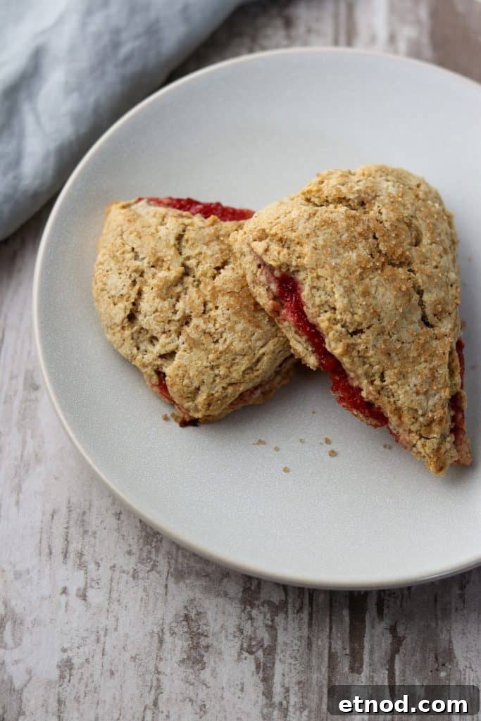 Two strawberry rhubarb scones stacked on a plate