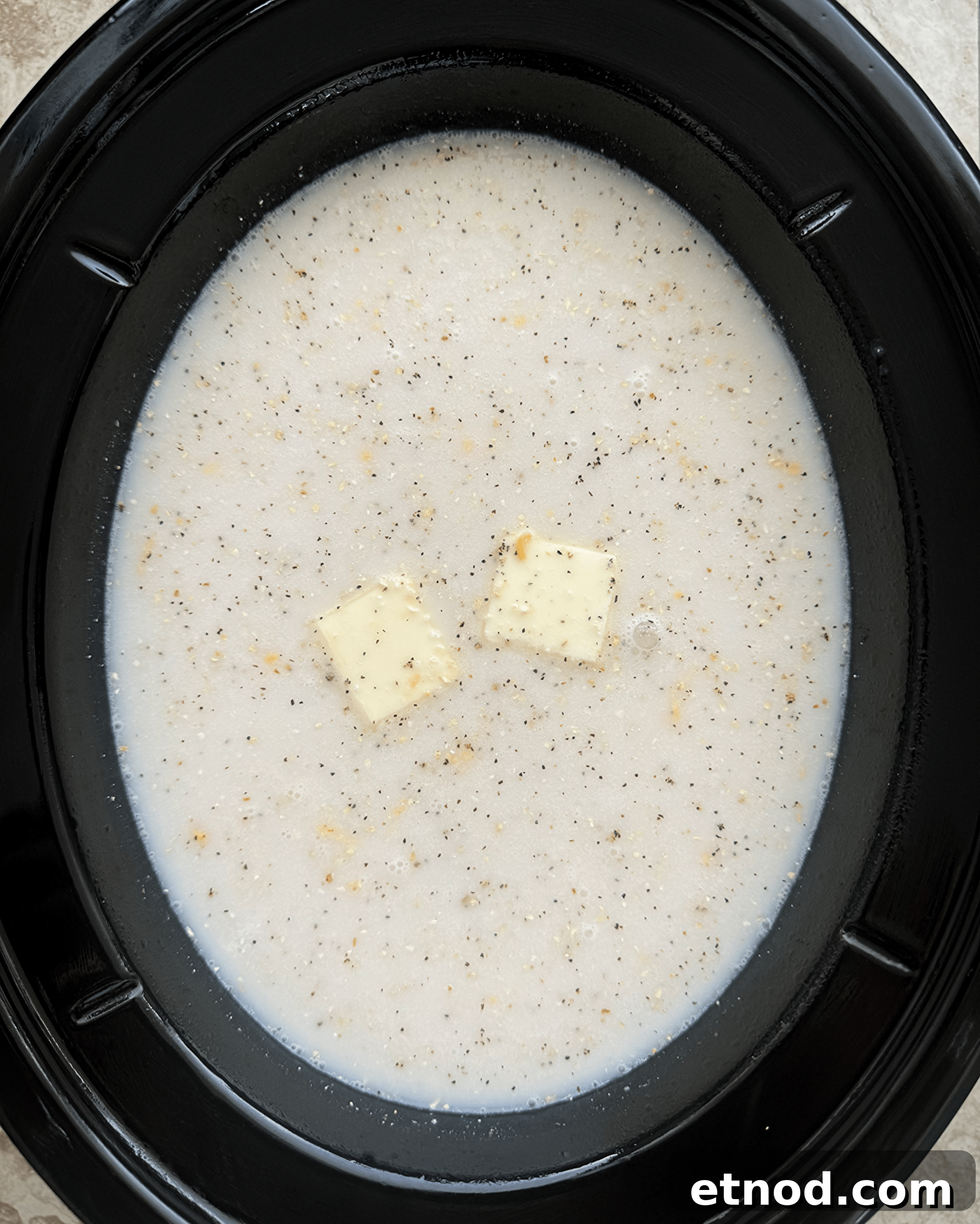 Creamy Slow Cooker Shrimp and Grits Recipe 4 overhead shot of uncooked grits in a black slow cooker