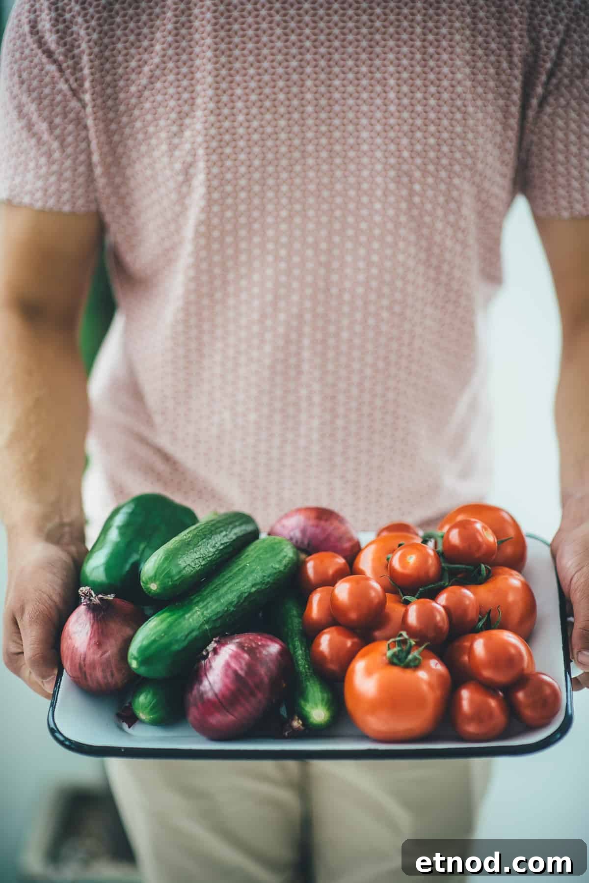 How to Make Authentic Greek Salad: Classic Recipe & Tips 7 a man holding a tray filled with cucumbers tomatoes and onions