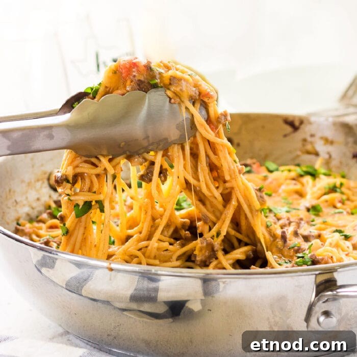 10 Simple Dishes You Can Make with a Can of Soup 6 A closeup of tongs lifting a serving of taco spaghetti out of the pan.