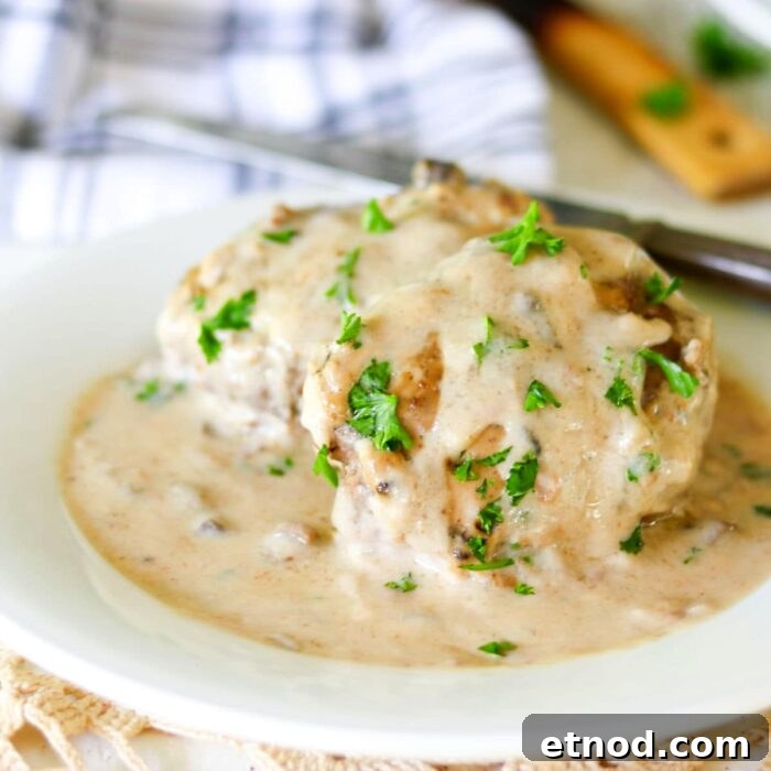 10 Simple Dishes You Can Make with a Can of Soup 9 Closeup of salisbury steak covered in creamy gravy on a white plate.